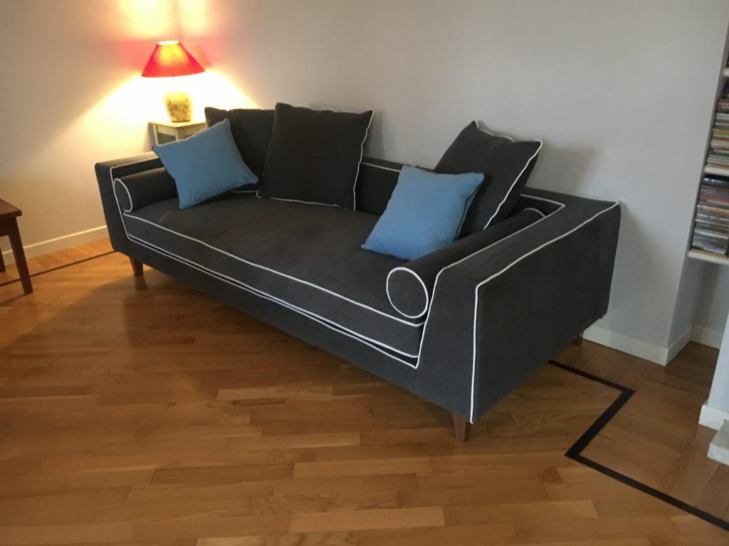 Dettaglio del divano nero Tino Mariani, cuciture bianche a contrasto e cuscini blu in tessuto Made in Italy.